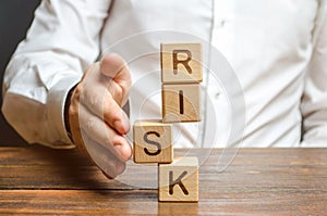 A man straightens a segment in an unstable tower of cubes labeled Risk. Risk management, cost assessment, and business