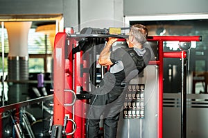 man strengthening his muscles by doing pull-up on horizontal bar in a fitness center