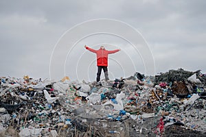 Man with stretched arms standing on landfill, environmental concept.