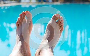 Man stretched legs at swimming pool with clear turquoise water