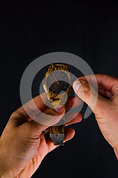 A man stretches out a wristwatch and adjusts the time.