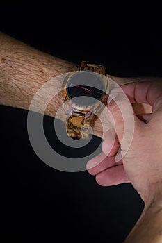 A man stretches out a wristwatch and adjusts the time.