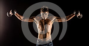 Man stretching arms outward doing a Standing Dumbbell Chest Fly. Studio composite over black.