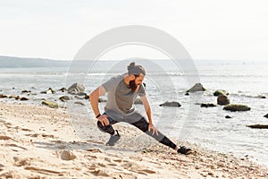 Man Stretching on Beach with Rocks and Hills in Background for Physical Activity photo
