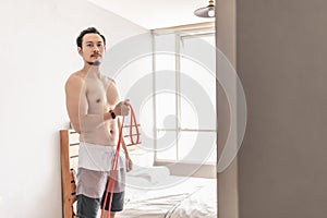 Man stretching his muscle in concept of workout at home with resistance band.