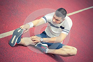 Man stretching leg on the running track