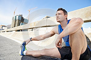 Man, stretching legs and runner in city, warm up for cardio workout and fitness outdoor. Athlete, sports and running in