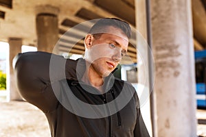 man stretching neck under bridge