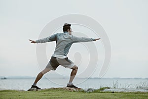 A man stretching before running. Young man workout before fitness training near the beach. Healthy and exercise warming up