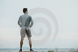 A man stretching before running. Young man workout before fitness training near the beach. Healthy and exercise warming up