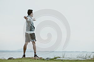 A man stretching before running. Young man workout before fitness training near the beach. Healthy and exercise warming up