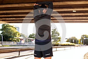 man stretching shoulder under bridge