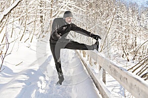 Man stretching on snow in forest, bautiful sunny winter day