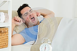 man stretching and yawning as he awakes in bed