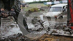 Man strike big nail with hammer, while worker uses track jack in slow motion. Try to get stucked car from mud and dirt.
