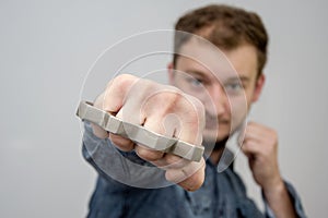 Man strikes brass knuckles on a light background, a prohibited weapon in a fight, heavy damage