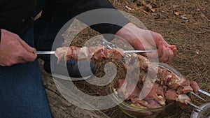 Man stringing kebab on a skewer. Cooking kebabs on the nature