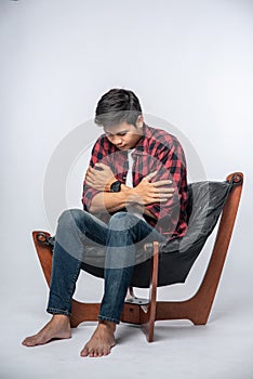 The man in a striped shirt sits sick and sits on a chair and crosses his arms