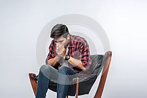 The man in a striped shirt sits sick and sits on a chair and crosses his arms