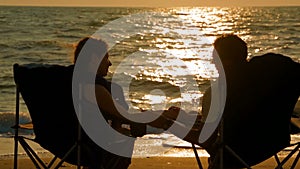 A man stroking a woman by the hand on the seashore