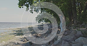 A man strolling by the water on a rocky shoreline amidst natural landscape