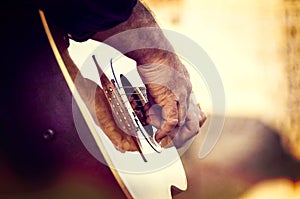 Man Strumming A Roundback Guitar Against Golden Background photo