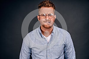 Man stuck with tough choice. Upset nervous and anxious handsome mature guy in glasses and denim shirt, biting lip and frowning