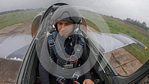 A man student in a flight school for the first time sits and open helmet and looks around. Gray blue fighter combat aircraft