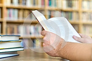 Man or student reading a book in public or school library.