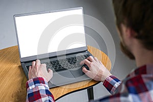Man student typing on grey laptop computer keyboard with white blank screen
