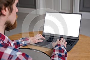 Man student typing on grey laptop computer keyboard with white blank screen