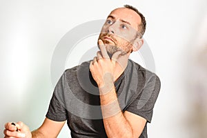 Man in studio, thoughtful hand resting on his chin, model expressions isolating white background