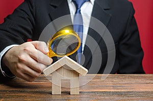 A man is studying a house through a magnifying glass. Fair value of real estate. Property valuation. Legal deal. Legality and