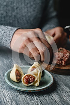 man stuffing some Catalan galets with ground meat