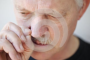 Man with stuffy nose pulls on a nostril photo