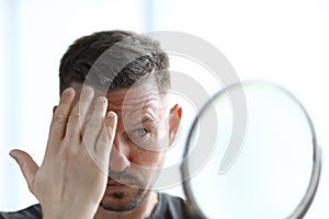 Man is styling his hair with gel in front of mirror.