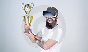 Man with stylish beard in VR glasses posing with 1st prize isolated on gray background. Happy bearded man holding golden