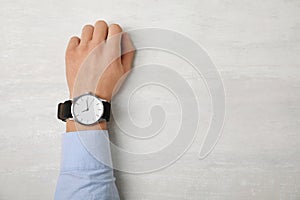 Man with stylish wrist watch at table, space for text