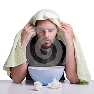 A man is suffering from the flu and inhales steam to get healthy isolated on white background