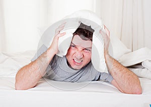 Man suffering hangover and headache with pillow on