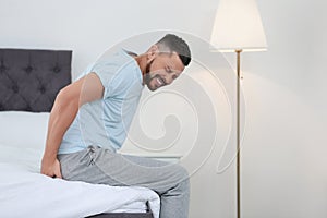Man suffering from hemorrhoid on bed photo