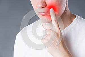 Man suffering from herpes virus on the lip, studio shot on gray background