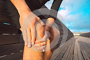 Man suffering from knee pain outdoors. Man massaging his knee because of injury