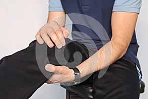 man suffering from knee pain. young man is holding his hands over his sick knee on a blue background. patella fracture.