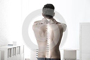 Man suffering from pain in spine in office. Black and white effect