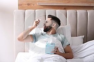 Man suffering from runny nose in bed