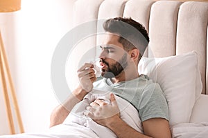 Man suffering from runny nose in bed