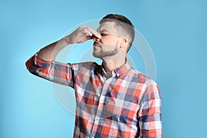 Man suffering from runny nose on light blue background