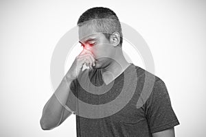 Man suffering from sinus pressure. Man touching his nose. Isolated on gray background. Healthcare and health problem concept