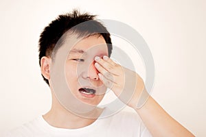 Man suffering from strong eye pain. portrait of young male feeling sick, nose pain and touching painful eyes.